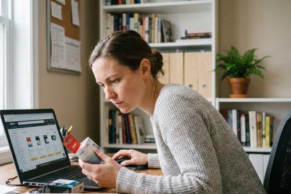 Femme comparant des cartouches d'encre avec une boutique en ligne sur son ordinateur portable dans un bureau à domicile