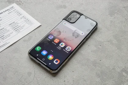 Samsung Galaxy S24 reconditionné posé sur une surface en béton gris avec une fiche technique visible en arrière-plan